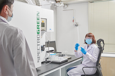 women with lab coat seating on chair looking at a man in lab cost